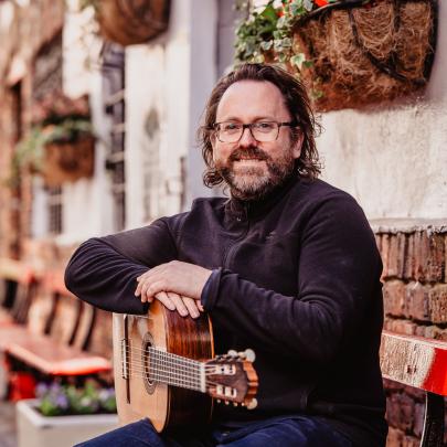 Paddy Anderson sitting on a bench with a guitar