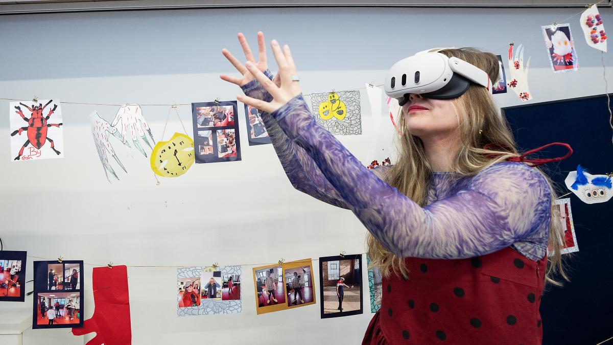 A woman wearing a VR headset reaches upwards